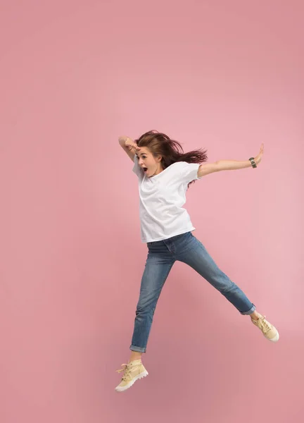 Frihet i rörelse. Ganska ung kvinna hoppa mot rosa bakgrund — Stockfoto