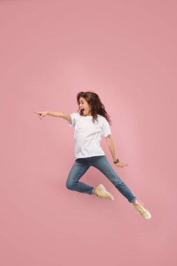 Hareketli bir özgürlük. Genç ve güzel kadın karşı pembe arka plan atlama