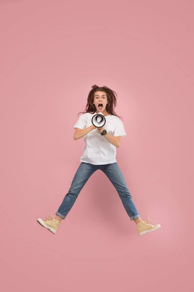 Schöne junge Frau springt mit Megafon isoliert über rosa Hintergrund — Stockfoto