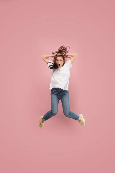 Freedom in moving. Pretty young woman jumping against pink background — Stock Photo, Image