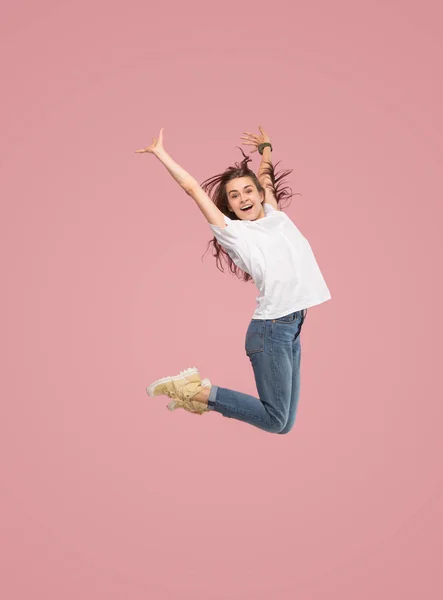 Liberdade em movimento. Mulher muito jovem pulando contra fundo rosa — Fotografia de Stock