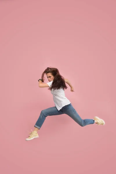 Liberdade em movimento. Mulher muito jovem pulando contra fundo rosa — Fotografia de Stock