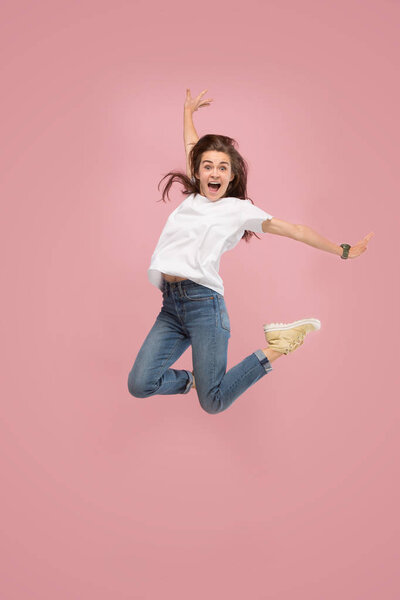 Freedom in moving. Pretty young woman jumping against pink background