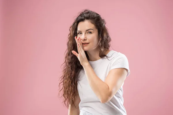 Die junge Frau flüstert ein Geheimnis hinter ihrer Hand über rosa Hintergrund — Stockfoto