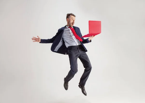 Изображение молодого человека на белом фоне с помощью ноутбука во время прыжка . — стоковое фото