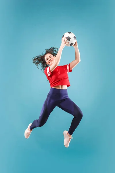 Avanti alla vittoria.La giovane donna come giocatore di calcio che salta e calcia la palla in studio sul rosa — Foto Stock