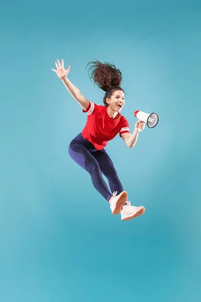 Mulher bonita pulando com megafone isolado sobre fundo vermelho — Fotografia de Stock