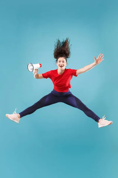 Vacker ung kvinna hoppa med MegaFon isolerade över röd bakgrund — Stockfoto