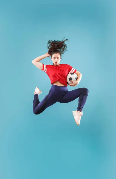 Forward to the victory.The young woman as soccer football player jumping and kicking the ball at studio on pink — Stock Photo, Image