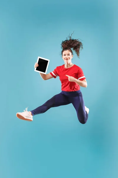 Podobu mladé ženy růžové pozadí pomocí přenosný počítač nebo tablet miniaplikaci při skákání. — Stock fotografie
