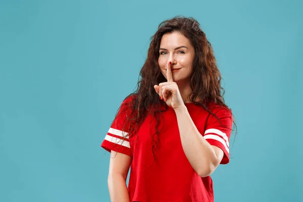 De jonge vrouw die een geheim achter haar hand fluisteren over blauwe achtergrond — Stockfoto