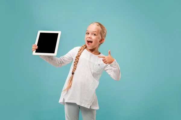 Маленька смішна дівчинка з планшетом на синьому фоні — стокове фото