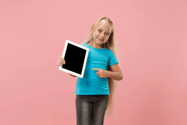 Niña divertida con tableta sobre fondo rosa — Foto de Stock