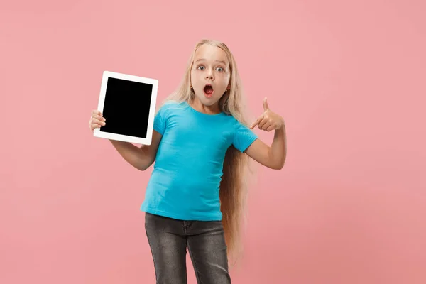 Niña divertida con tableta sobre fondo rosa — Foto de Stock