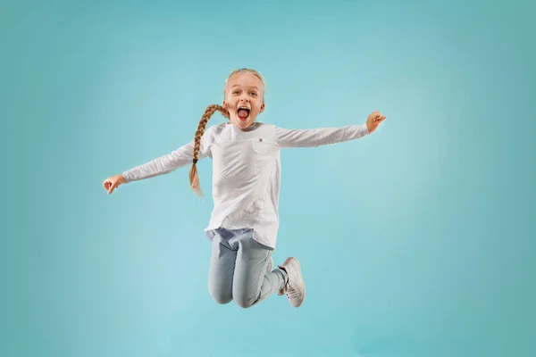 Schattig klein kind bij blauwe studio. Het meisje is springen en glimlachen. — Stockfoto