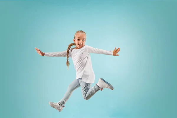 Adorable small child at blue studio. The girl is jumping and smiling. — Stock Photo, Image