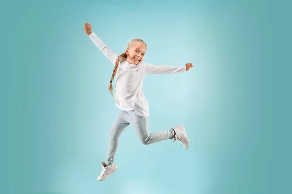 Adorable small child at blue studio. The girl is jumping and smiling. — Stock Photo, Image