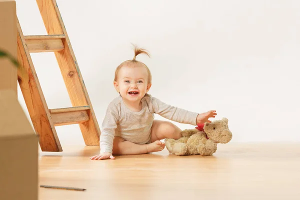 Friendly blue eyed baby girl sitting on the floor indoors — Stock Photo, Image