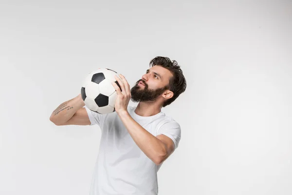 Jovem jogador de futebol com bola na frente do fundo branco — Fotografia de Stock