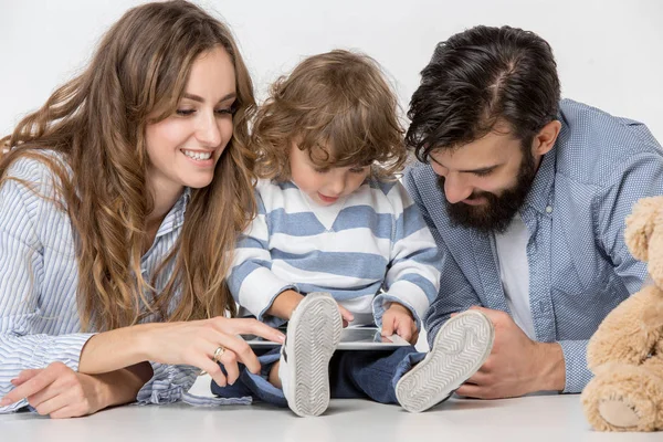 Sorrindo família sentados juntos em estúdio e assistindo seus desenhos animados favoritos no laptop — Fotografia de Stock