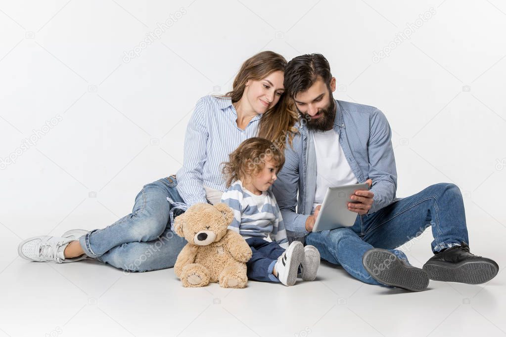 Smiling family sitting together in studio and watching their favorite cartoons on laptop