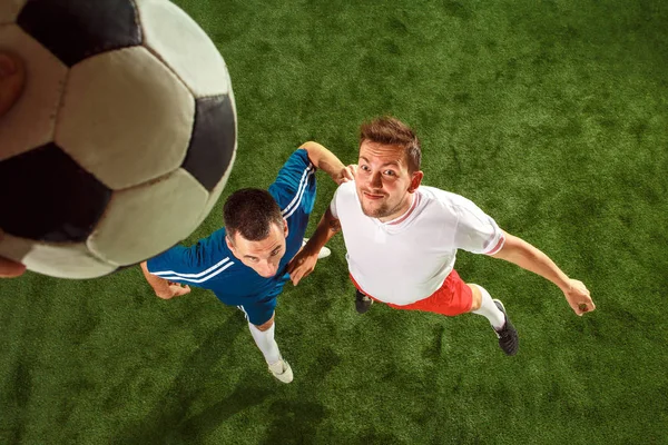 Футболісти тягнуться до м'яча на фоні зеленої трави — стокове фото