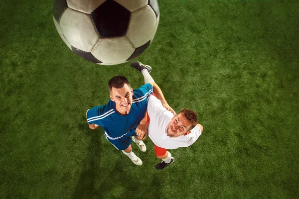 Футболісти тягнуться до м'яча на фоні зеленої трави — стокове фото