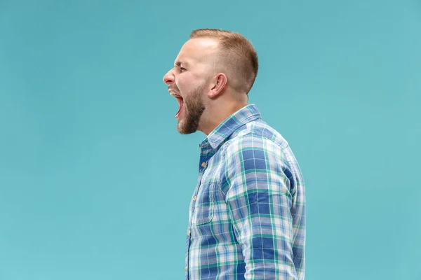 Il giovane uomo arrabbiato emotivo urla sullo sfondo dello studio — Foto Stock