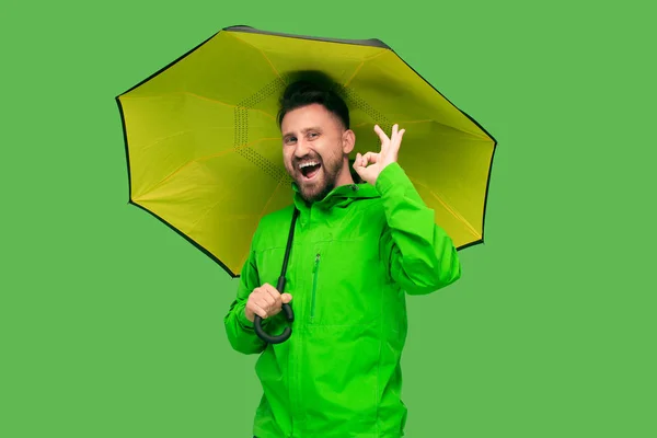 Schöner bärtiger junger Mann mit Regenschirm und Blick in die Kamera isoliert auf weiß — Stockfoto