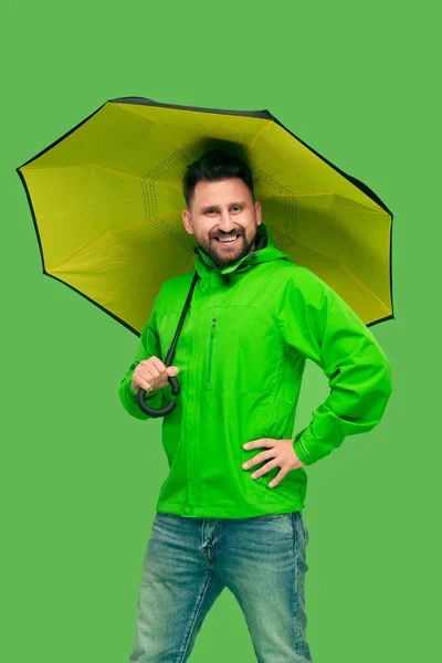 Schöner bärtiger junger Mann mit Regenschirm und Blick in die Kamera isoliert auf weiß — Stockfoto