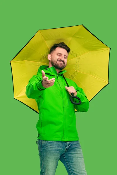 Pohledný vousatý mladý muž, držící deštník a při pohledu na fotoaparát izolované na bílém — Stock fotografie