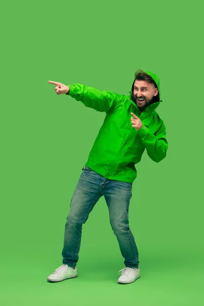 Guapo barbudo joven mirando cámara aislada en verde — Foto de Stock