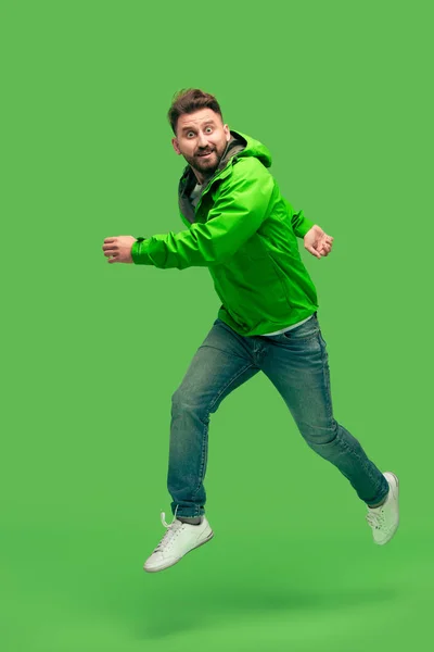 Pohledný mladý vousatý muž běžící izolované na zelené — Stock fotografie