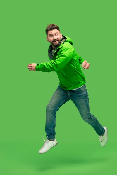 Handsome bearded young man running isolated on green — Stock Photo, Image