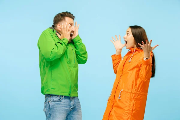 Молодий здивований зв'язок позує в студії в осінніх куртках ізольовані на синьому — стокове фото