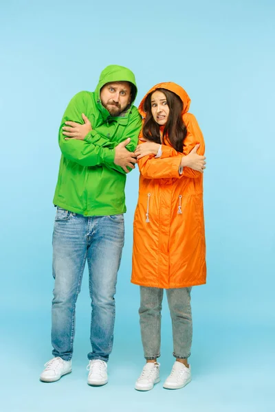La joven pareja posando en el estudio en chaquetas de otoño aisladas en azul — Foto de Stock