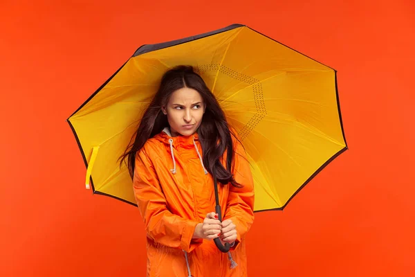 A jovem posando no estúdio em casaco de outono isolado no vermelho — Fotografia de Stock