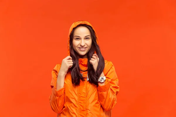 Das junge Mädchen posiert im Atelier in Herbstjacke isoliert auf Rot — Stockfoto
