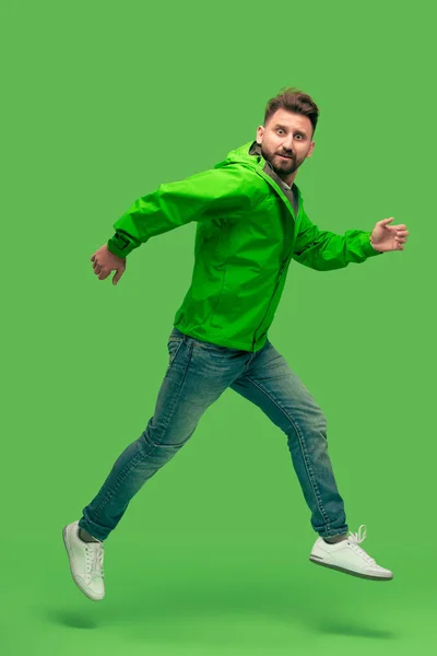 Handsome bearded young man running isolated on green — Stock Photo, Image
