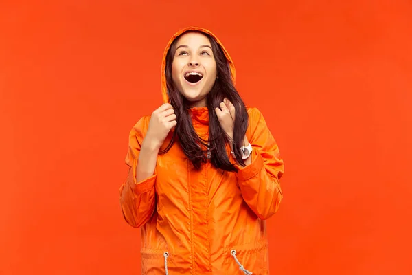 Den unga flickan som poserar på studio i höst jacka isolerade på röd — Stockfoto