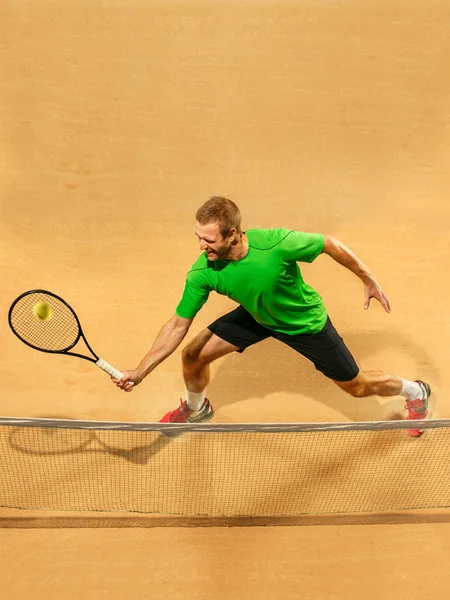 El jugador de salto, hombre caucásico en forma, jugando al tenis en la cancha de tierra —  Fotos de Stock