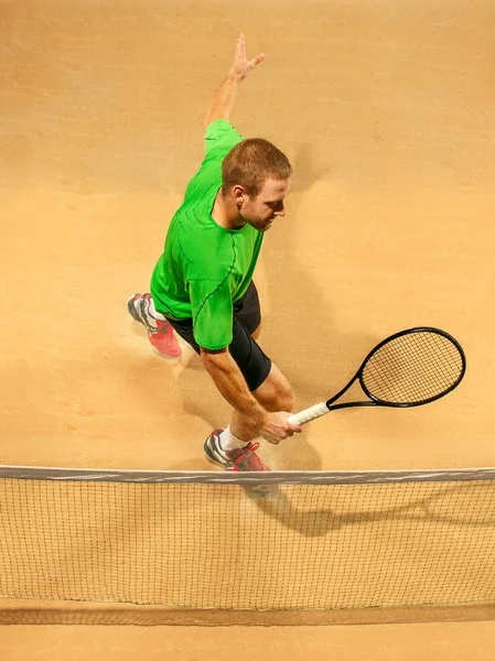 Прыгун, кавказский спортсмен, играет в теннис на земной площадке. — стоковое фото