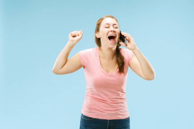 Genç güzel kadın mavi renk arka plan üzerinde cep telefonu studio kullanarak
