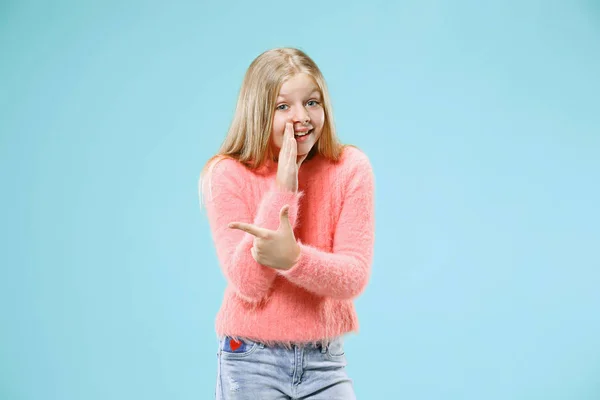 Den unga tonåring flicka viskar en hemlighet bakom hennes hand över Blå bakgrund — Stockfoto