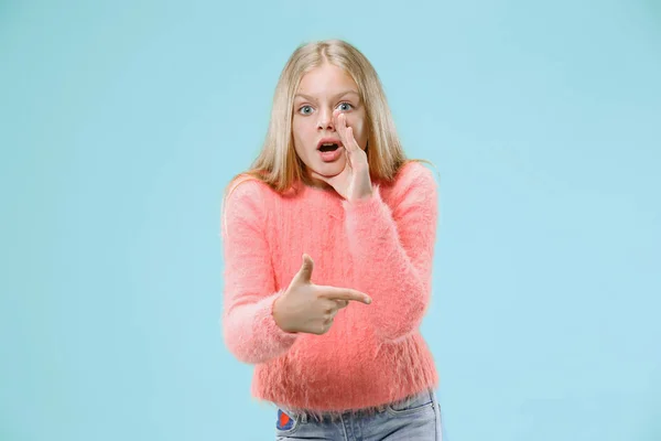 A jovem adolescente sussurrando um segredo atrás de sua mão sobre fundo azul — Fotografia de Stock