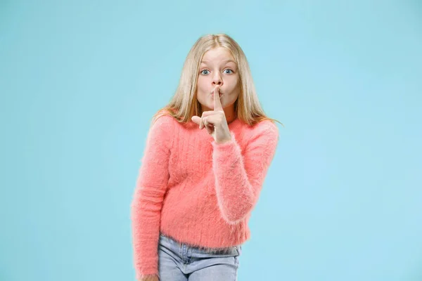 Den unga tonåring flicka viskar en hemlighet bakom hennes hand över Blå bakgrund — Stockfoto