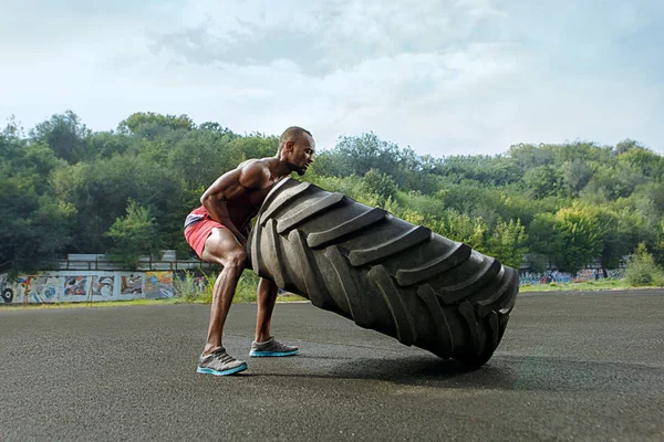 Stattliche Afrikanisch Amerikanisch Muskulös Mann Flipping Groß Reifen Outdoor — Stockfoto