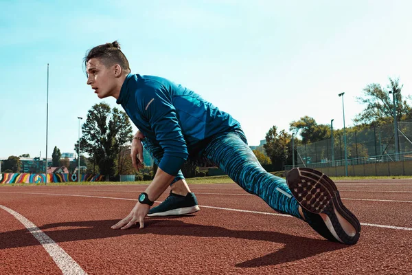 Man runner stretching legs preparing for run training on stadium tracks doing warm-up — Stock Photo, Image