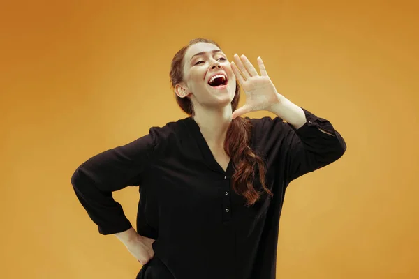 Geïsoleerd op oranje jonge casual vrouw schreeuwen in studio — Stockfoto