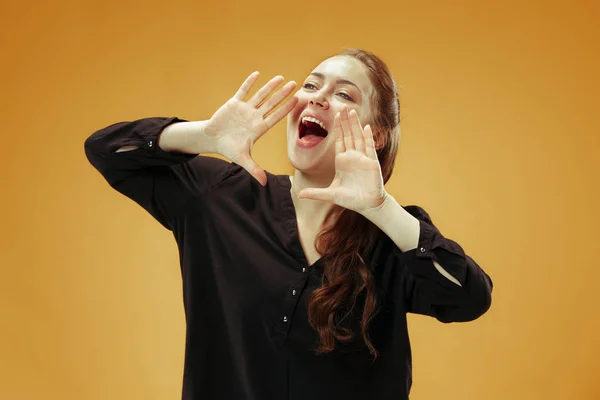 Isolated on orange young casual woman shouting at studio — Stock Photo, Image